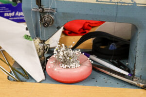 pins and sewing machine next to clothing rack