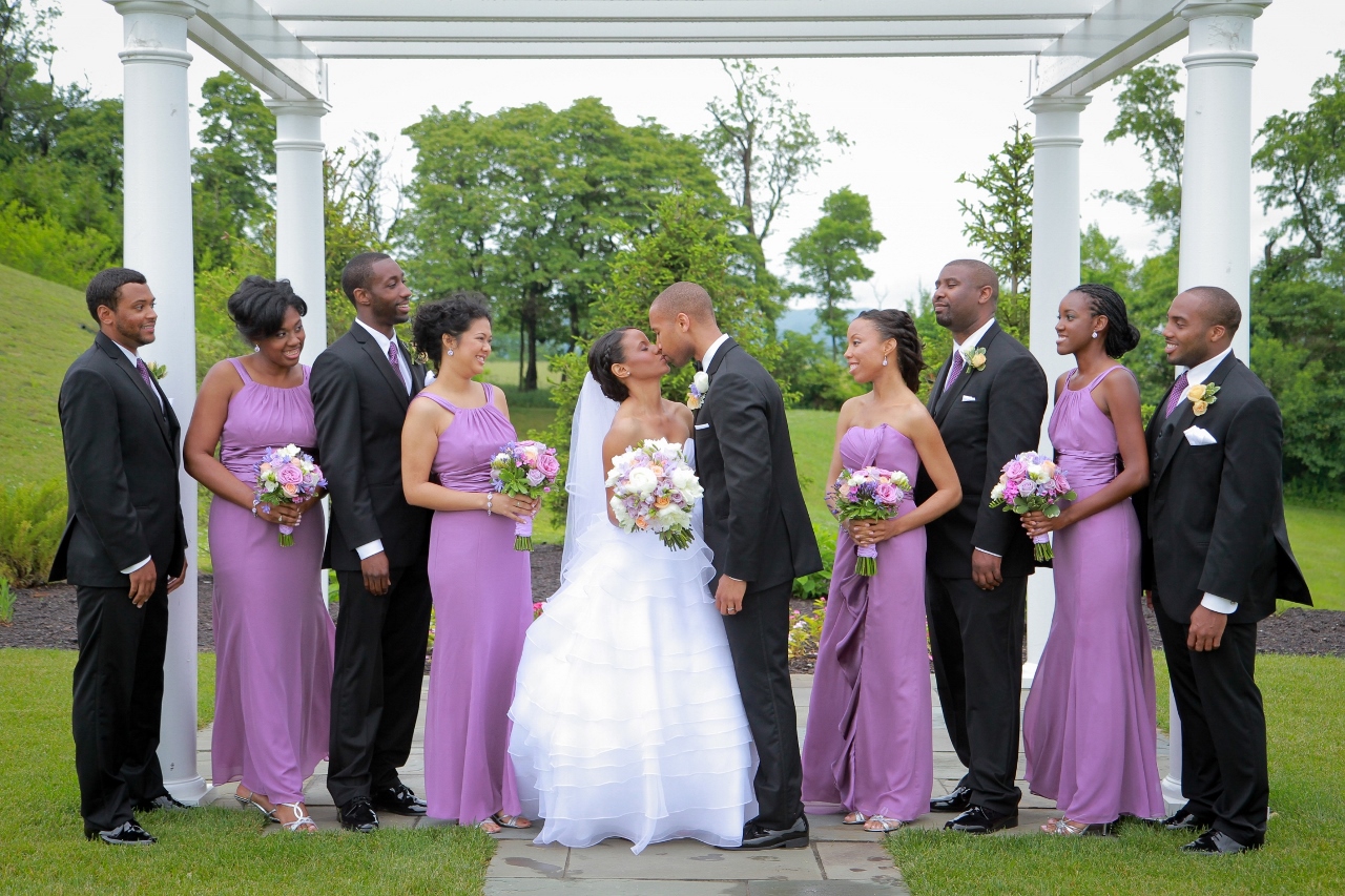 bridge and groom kissing in front of bridemaids and groomsmen